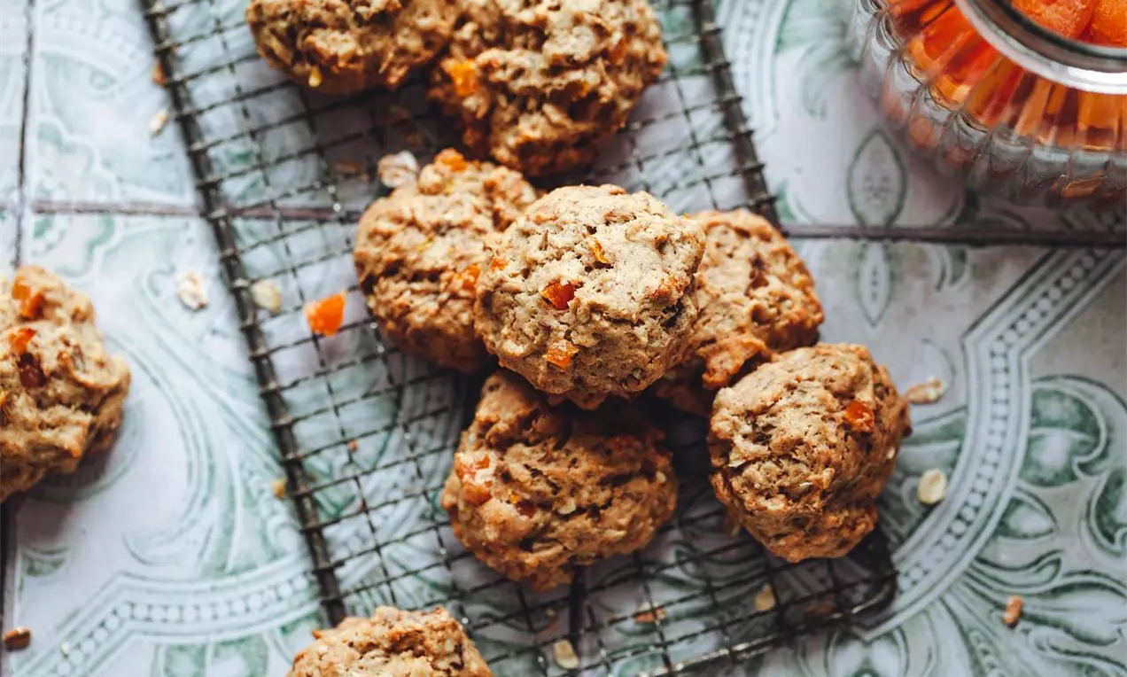 sušienky so sušenými marhuľami naaranžované na pekárskej mriežke na modrých dlaždiciach.