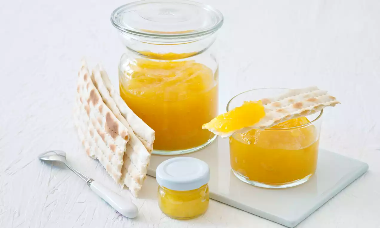 Piňa Colada džem v pohároch z číreho skla, žiarivo žltej farby, s plátkami chrumkavého pečiva na svetlom podklade