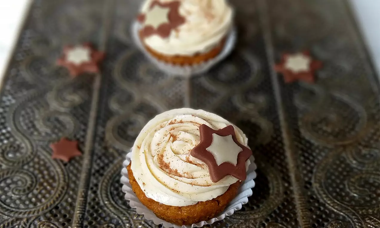 Perníkové cupcakes s jemným svetlým krémom dozdobené kakaovými hviezdičkami, uložené na zdobenom kovovom podnose s ďalšími hviezdičkami