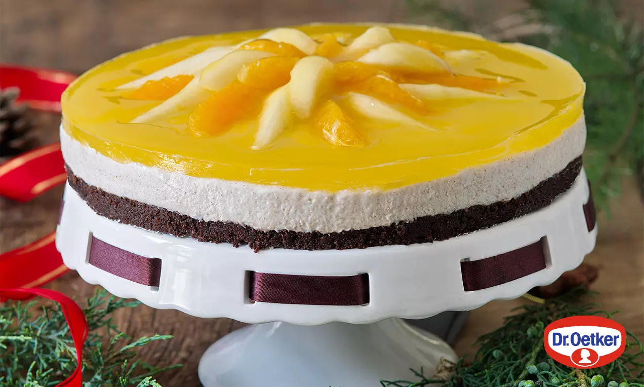 Adventná torta s tmavým kakaovým korpusom, krémovou strednou vrstvou a vrchom z lesklého žltého želé ozdobeným plátkami ovocia na bielom podnose